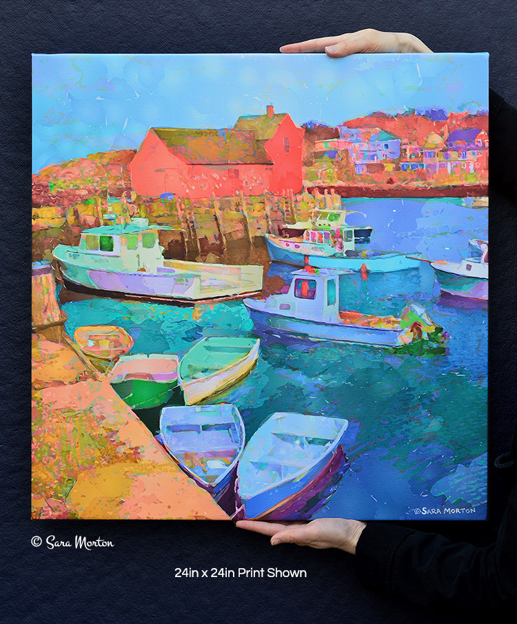 A colorful 24in x 24in art print of Rockport MA on canvas held by hands for scale, depicting a scene with boats docked in a harbor, primarily in shades of blue and green, with buildings in the background.