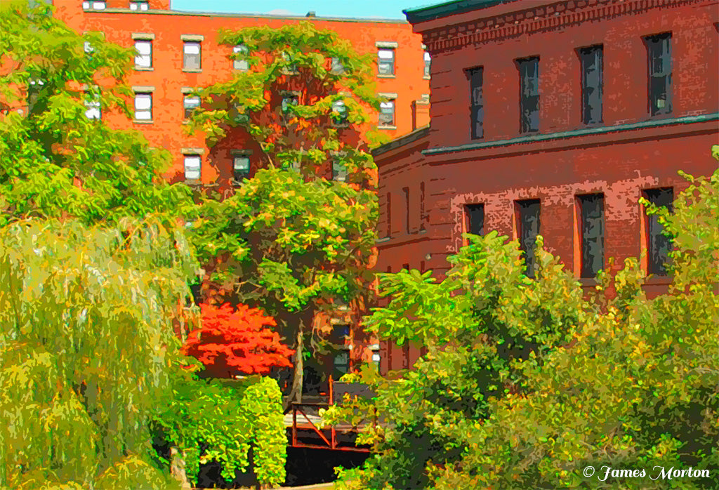 Detail view of Baker’s Chocolate Mills showing red brick mill buildings and riverside trees along the Neponset River in Milton, Massachusetts.
