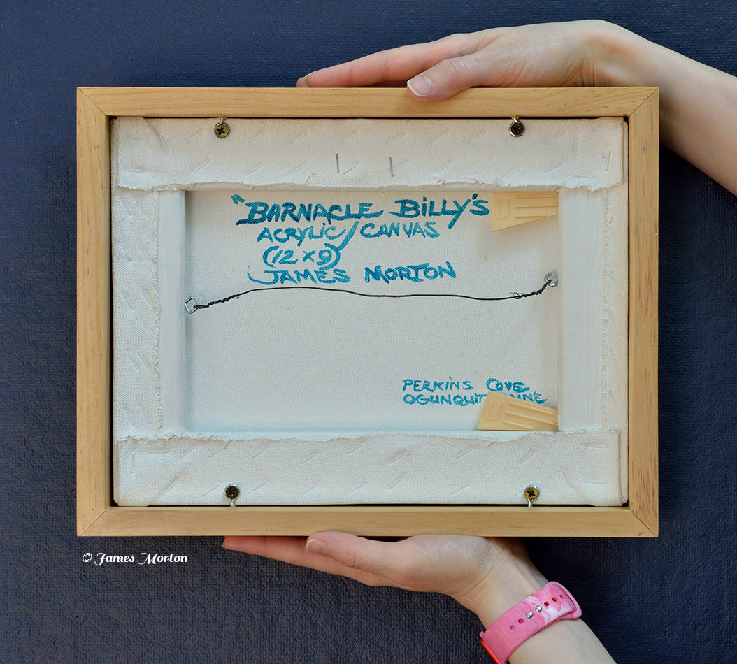 Back of framed original acrylic painting on canvas titled Barnacle Billy's, depicting Perkins Cove in Ogunquit, Maine. Hand signed, titled, labeled by the artist, wired and ready to hang, shown held for scale.