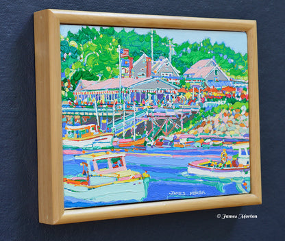 Left side angle view of a framed original Maine coastal painting depicting Barnacle Billy's restaurant at Perkins Cove in Ogunquit with fishing boats, blue harbor water, and surrounding green trees.