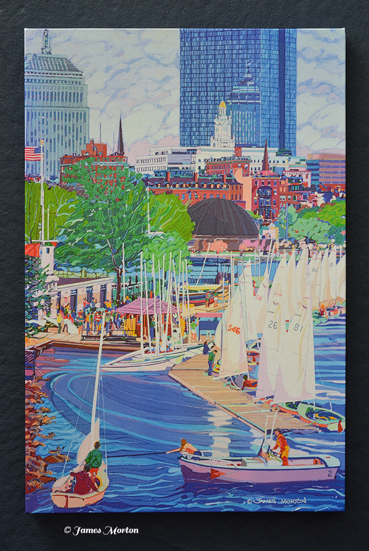 Ready-to-ship Boston skyline canvas print featuring Community Boating Boathouse, sailboats on the Charles River, the Charles River Esplanade, Hatch Shell, Back Bay skyline, and John Hancock Tower. Artist signature by James Morton visible in the lower right.

