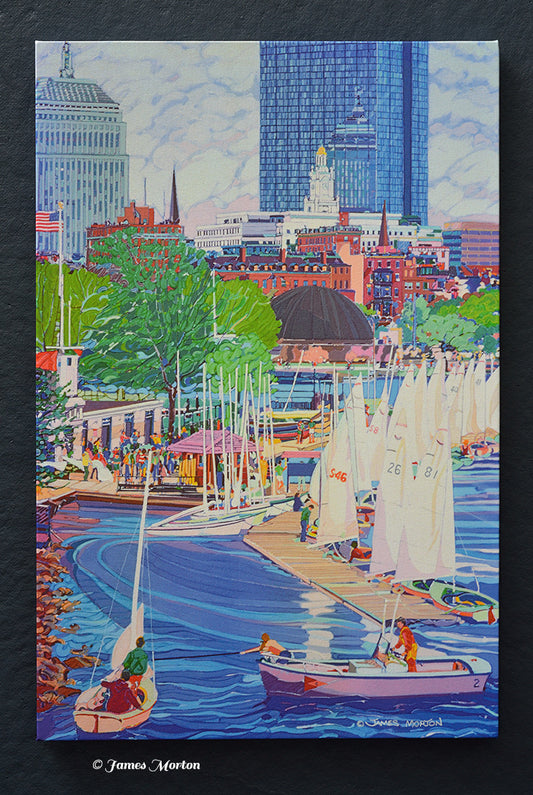 Ready-to-ship Boston skyline canvas print featuring Community Boating Boathouse, sailboats on the Charles River, the Charles River Esplanade, Hatch Shell, Back Bay skyline, and John Hancock Tower. Artist signature by James Morton visible in the lower right.
