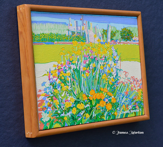 Framed original Wellfleet, Massachusetts landscape painting depicting a vibrant flower garden with yellow, pink, and orange blossoms in the foreground, green grass, and a tidal marsh with blue water and a distant small boat dock.