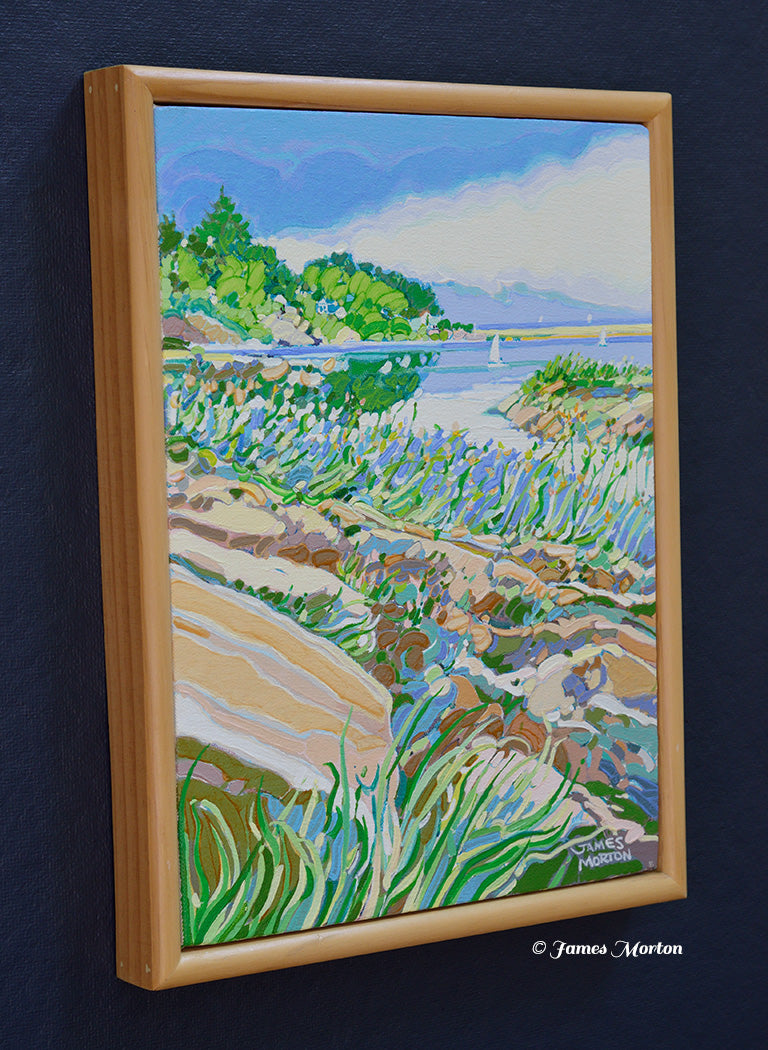 Left angle view of Ocean Pond, an original acrylic painting by James Morton depicting Ogunquit's Marginal Way with rocky Maine coastline, beach grasses, green trees, calm ocean water, and billowing clouds in a light wood frame.