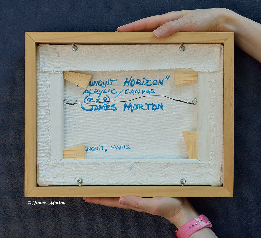 Back of the framed original acrylic painting Ogunquit Horizon, hand signed, titled, and labeled by artist James Morton. Original Maine coastal artwork on canvas, wired, and ready to hang, shown held for scale.