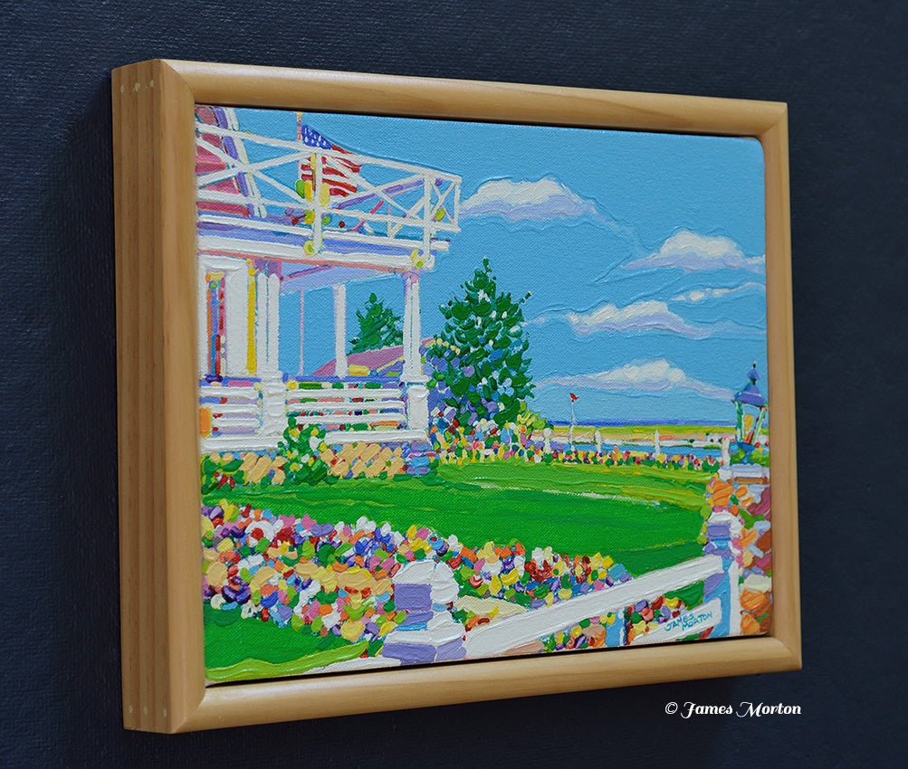 Left side angle of a framed original Maine coastal painting featuring a white Colonial inn, colorful flower garden, wrap-around porch, trees, bright blue sky, and hints of the Ogunquit coastline. Light pine wood frame with artist signature visible.